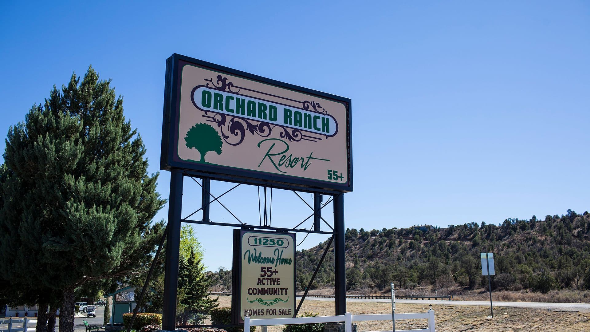 The grounds and welcome entrance at Orchard Ranch RV Resort with the high-country hills beyond.